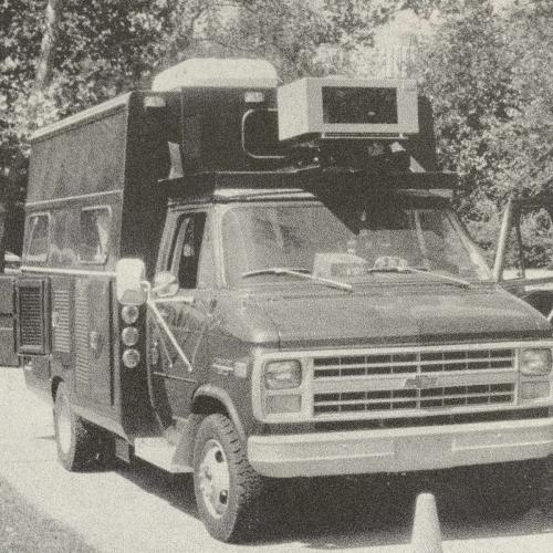 A black and white image of a Chevrolet box truck with a sensor affixed to the front above the windshield.